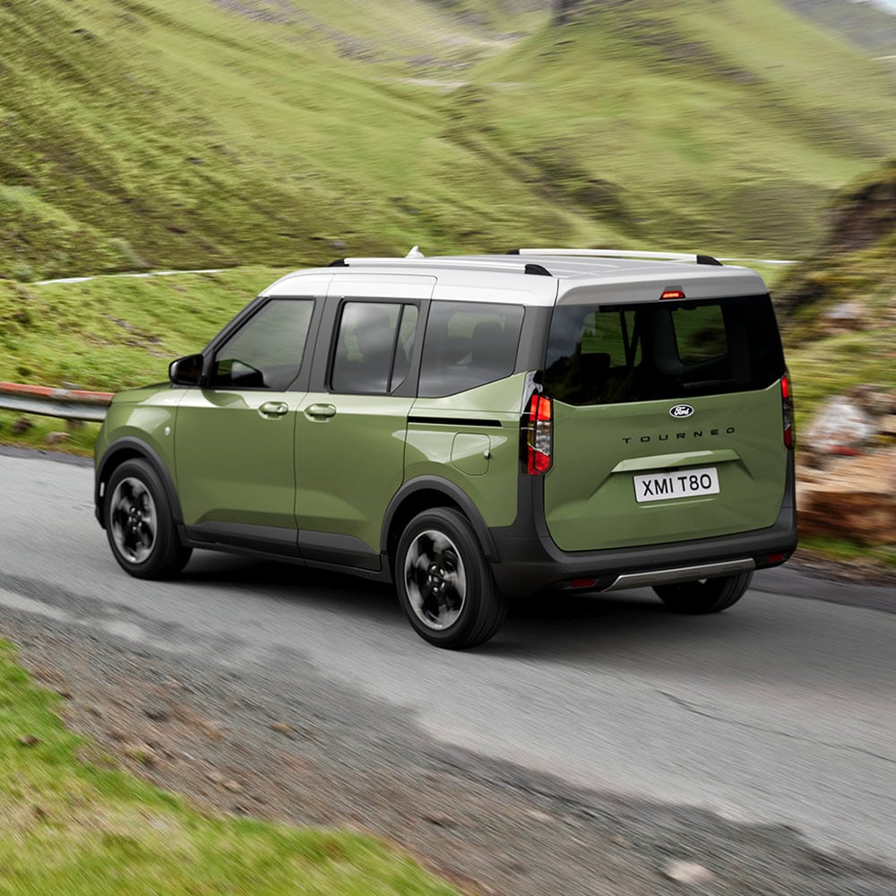 1000x1000 image of a green Ford Courier driving on a mountain road.