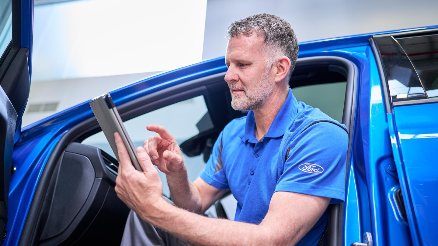 Técnico Ford sentado en un coche azul