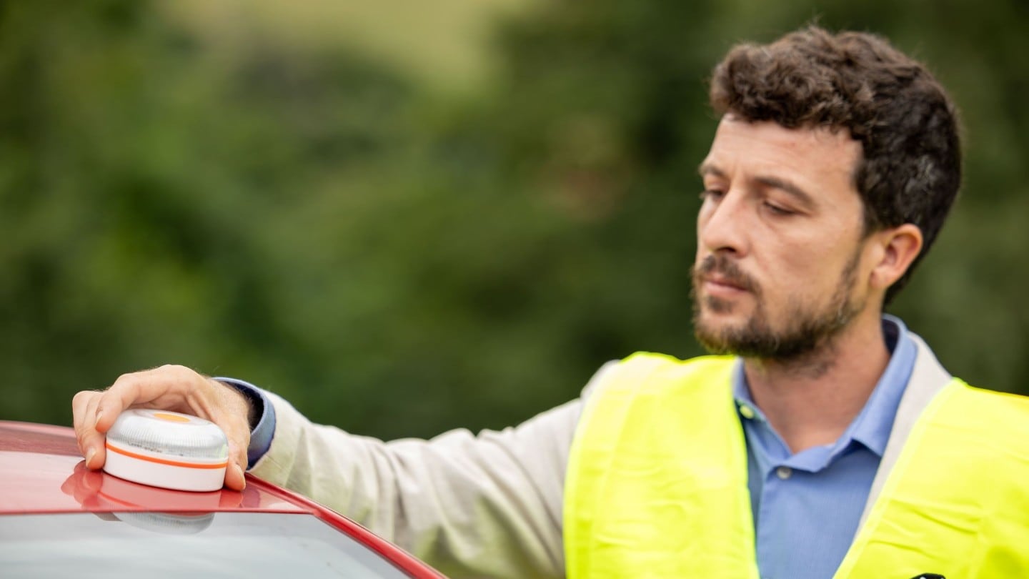 Un hombre y una mujer están cargando equipaje en el maletero de un SUV verde aparcado.