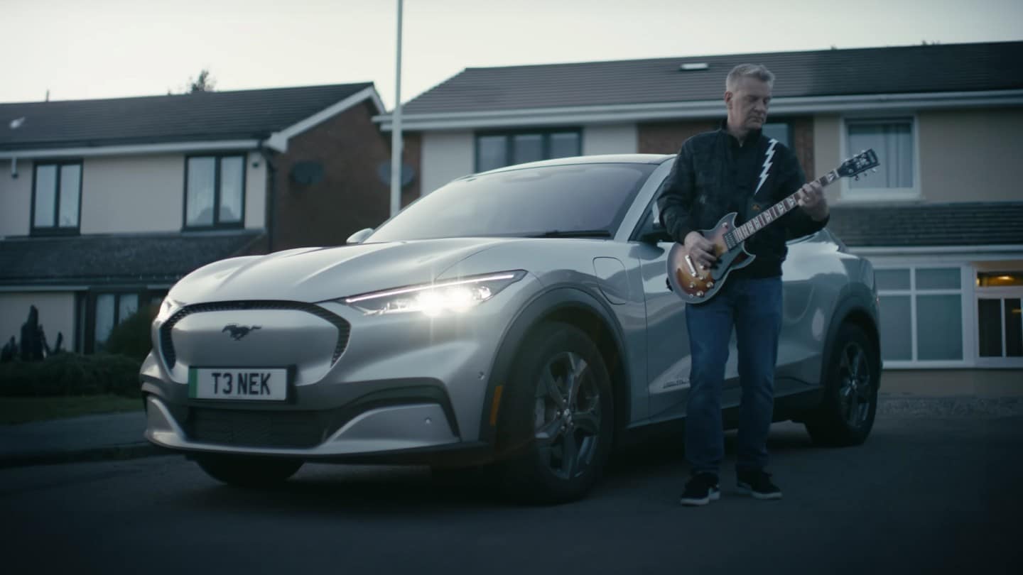 El músico Peter Steer aparece con su guitarra junto a su Mustang Mach-E.