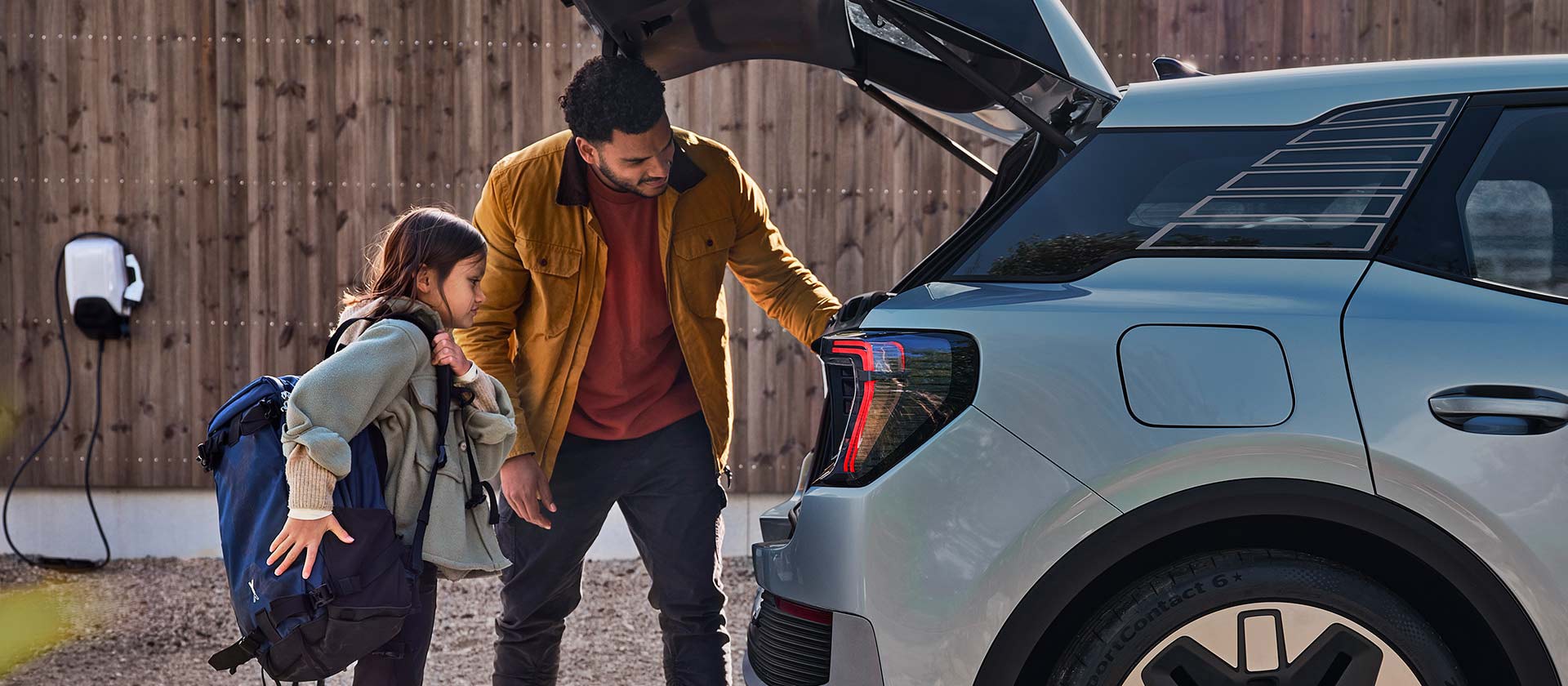 Una familia cargando el maletero de un Ford Explorer eléctrico azul.