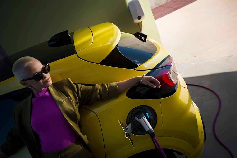 Una persona cargando un coche eléctrico Ford Capri amarillo.