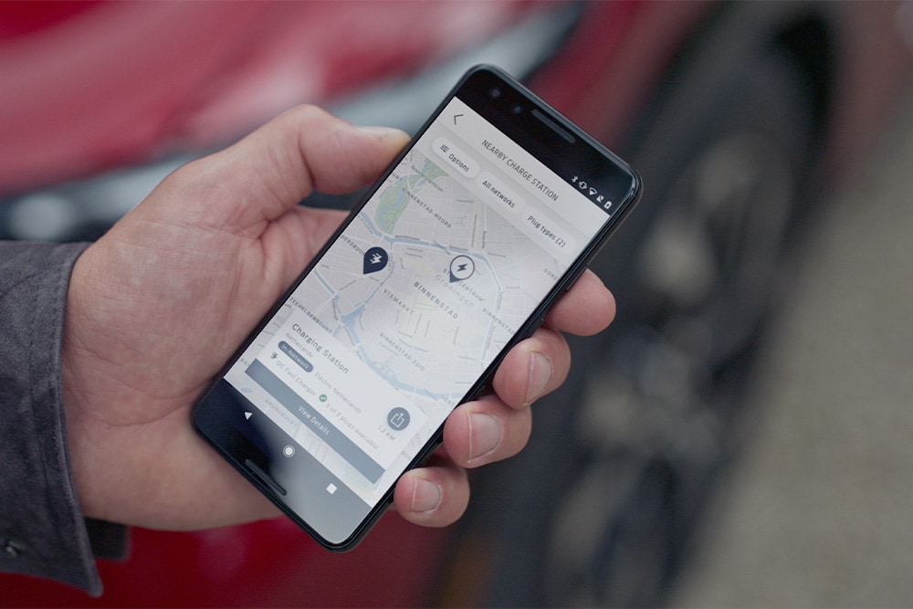 Un teléfono inteligente que muestra la aplicación FordPass™ con puntos de carga cercanos para la carga pública de Ford EV.
