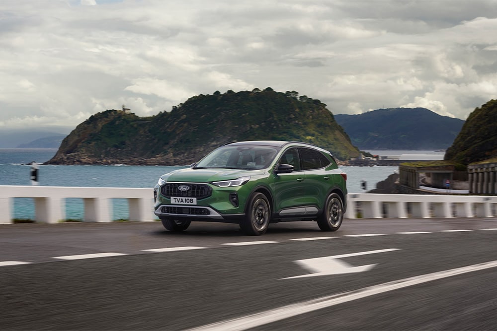 Un Ford Kuga híbrido autorrecargable verde que circula por una carretera pintoresca.