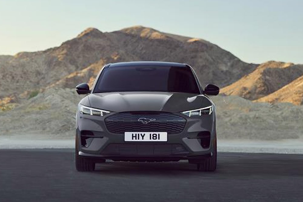 Vista delantera de un Ford Mustang Mach-E negro, aparcado frente a un paisaje montañoso.