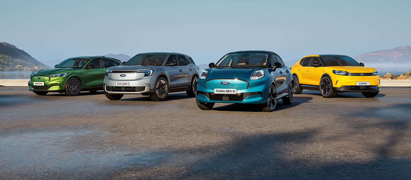 Una colección de diferentes coches eléctricos Ford estacionados en un paisaje costero escarpado.