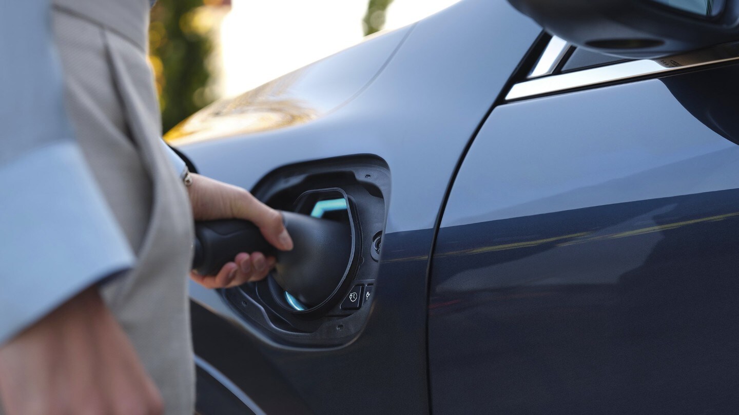 Close-up of connecting a charging cable to an electric car