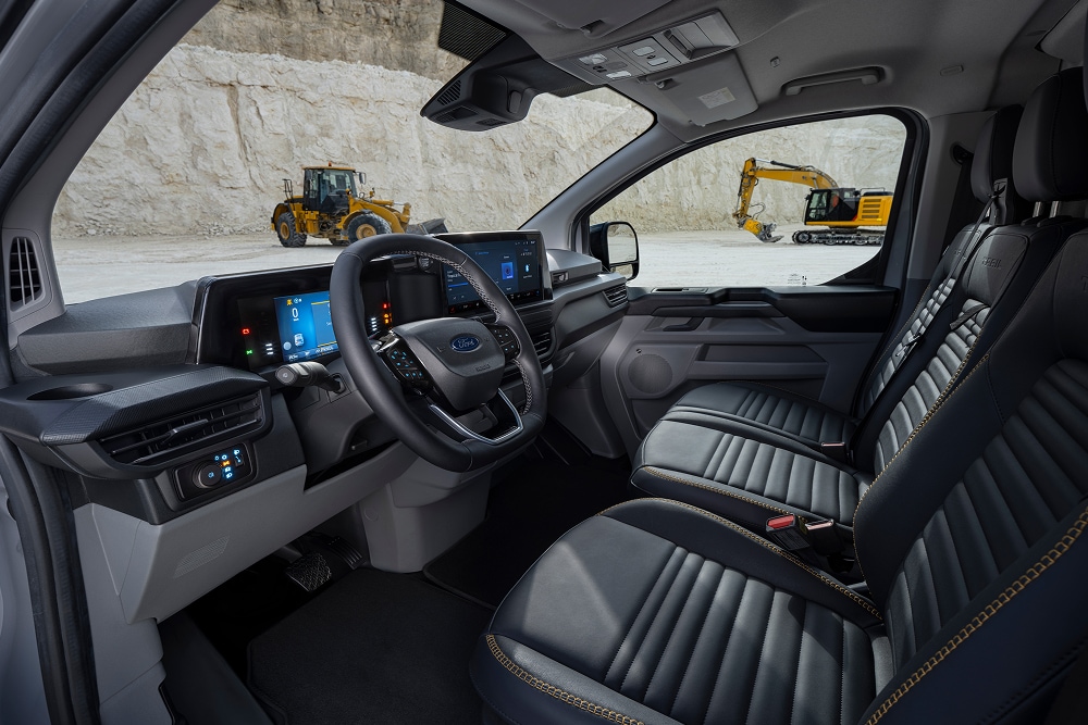 Imagen del interior de una furgoneta eléctrica Ford E-Transit Custom, estacionada en una cantera, en la que se ven los asientos y el volante.