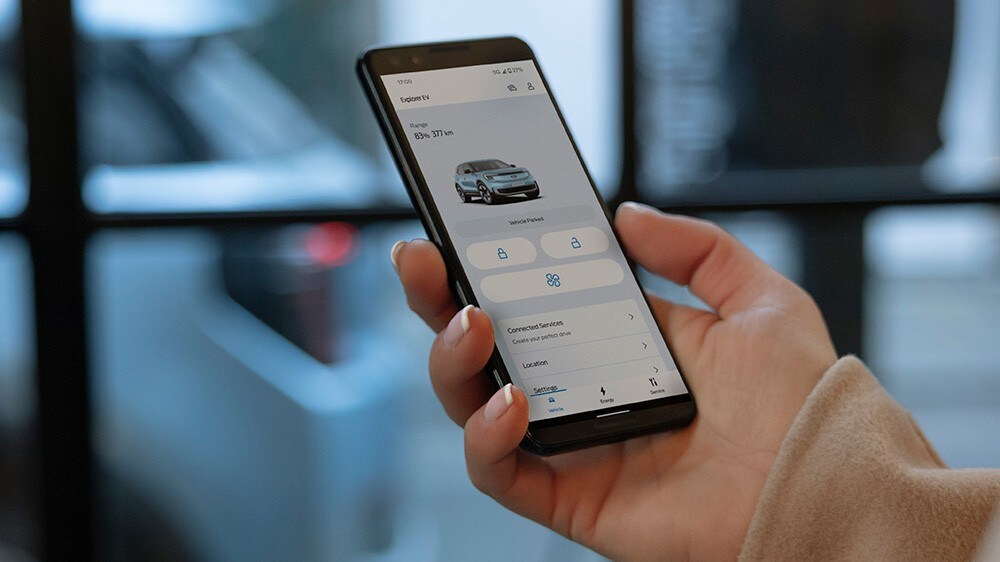 Imagen de una mano sujetando un teléfono móvil y utilizando la aplicación FordPass.