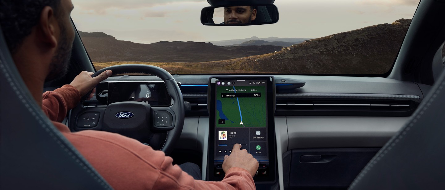 Hombre sentado en el asiento del conductor del Ford Explorer manipulando la pantalla táctil SYNC.