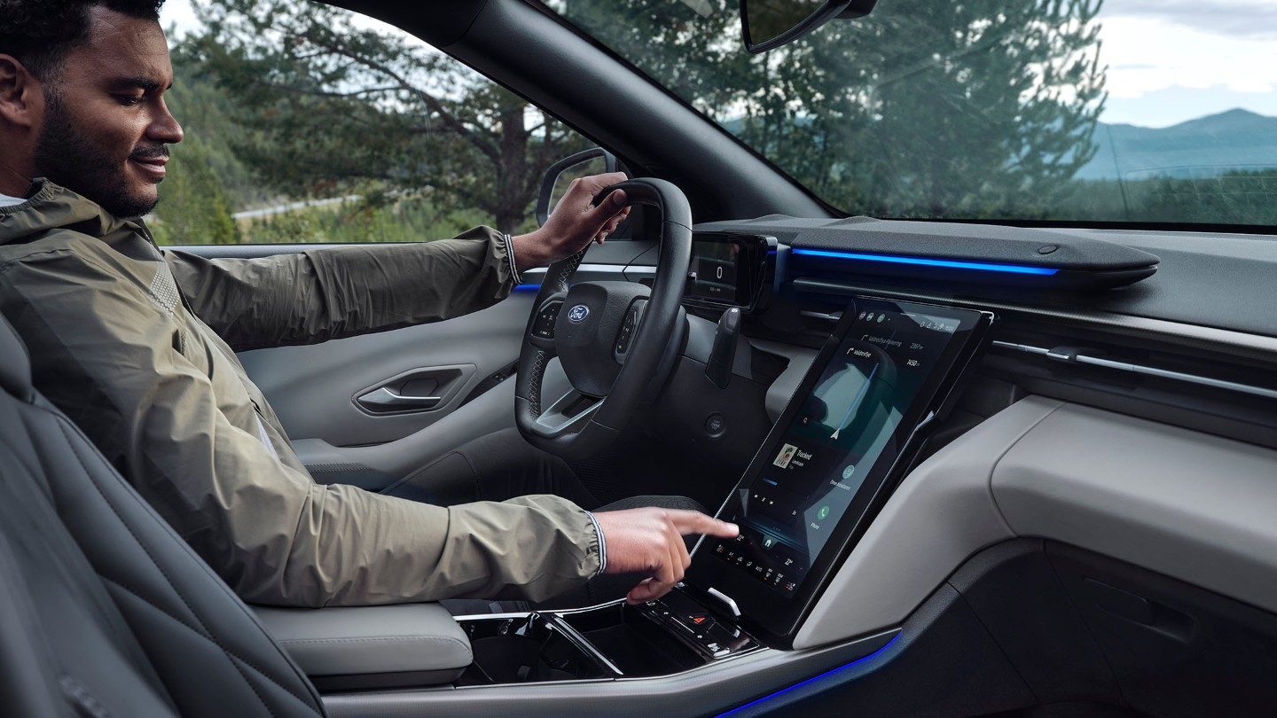 Hombre sentado en el asiento del conductor del Ford Explorer manipulando la pantalla táctil SYNC.