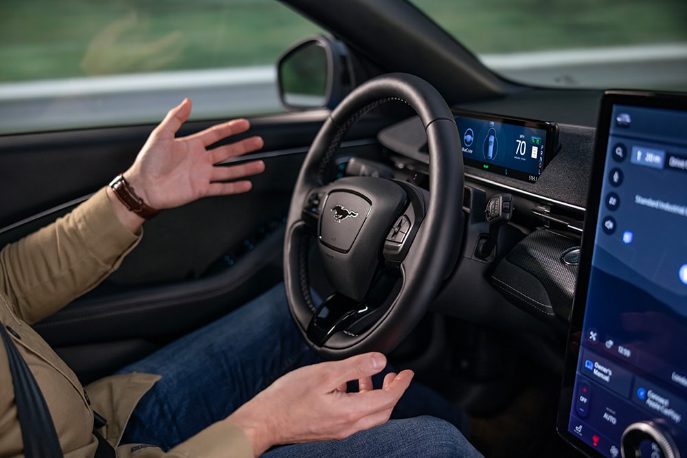 Una persona en el asiento del conductor de un automóvil con las manos fuera del volante.