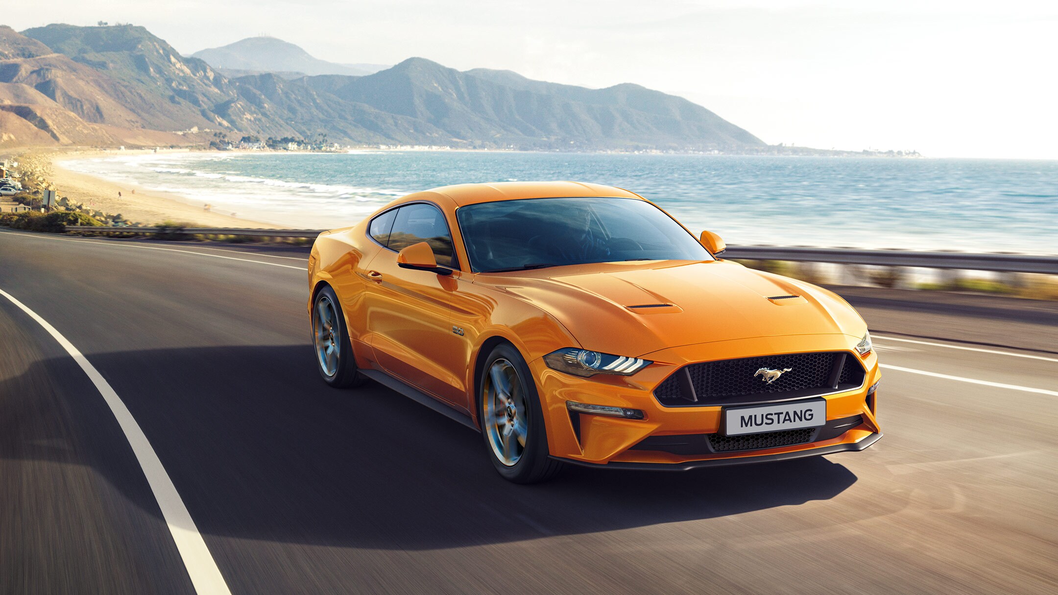 Yellow Ford Mustang on road by sea