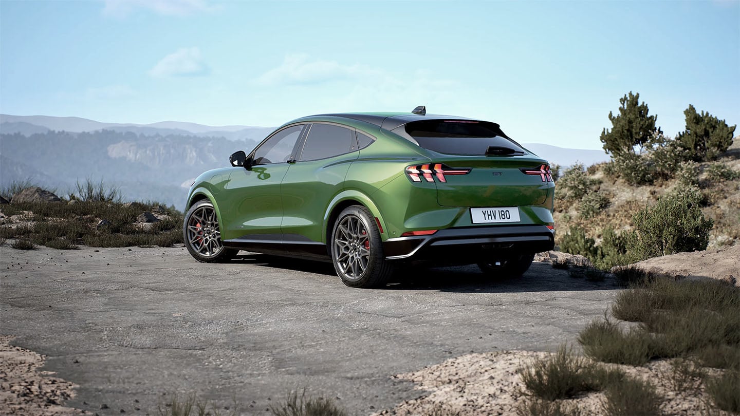 La parte posterior de un Ford Mustang Mach-E GT en Eruption Green estacionado en una carretera de montaña.