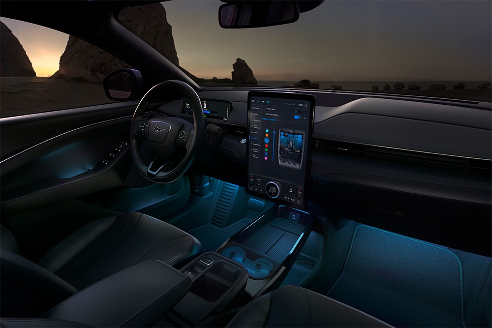 El interior del Ford Mustang Mach-E por la noche, con la pantalla táctil SYNC 4 de 15,5" y la iluminación LED ambiental en color azul.