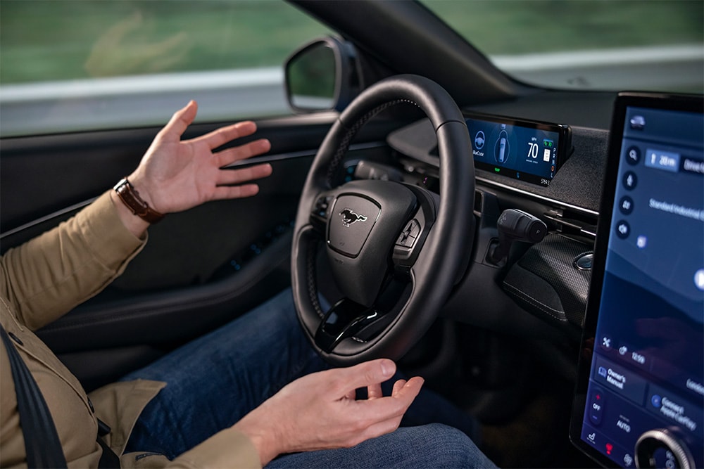 Un par de manos se ciernen sobre el volante del Mustang Mach-E, demostrando la tecnología de conducción autónoma BlueCruise