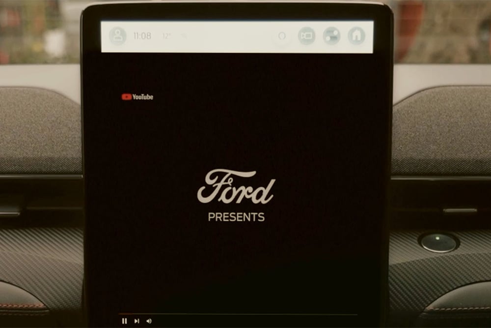 Un primer plano de la pantalla táctil SYNC 4 de 15,5" con un gráfico que reza «Ford presents» y demuestra la función de retransmisión de vídeo dentro del vehículo.