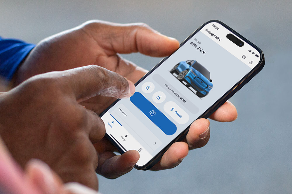 Un primer plano de un iPhone que muestra la aplicación FordPass, con un gráfico de un Ford Mustang Mach-E y varios botones de la aplicación.