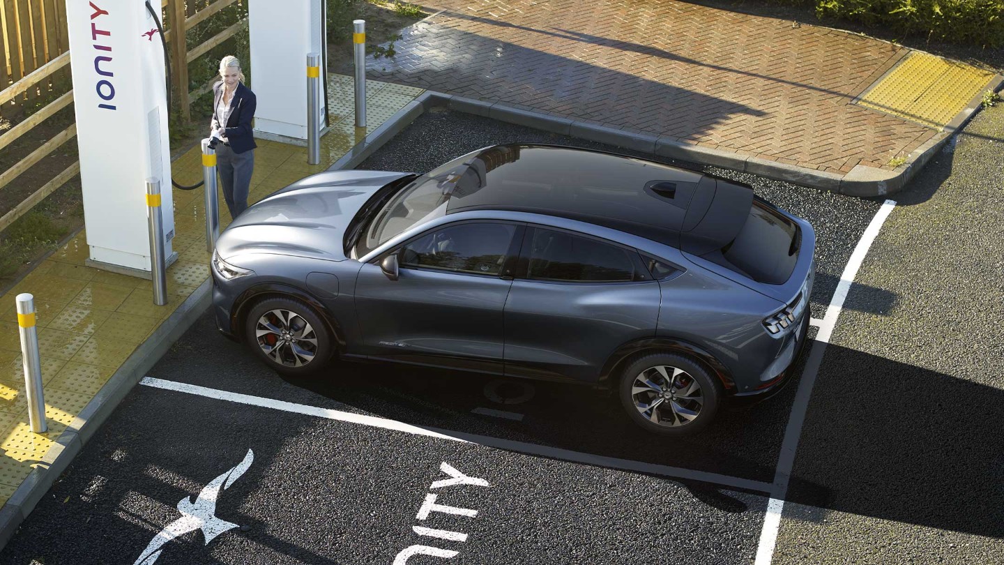 Una mujer cargando un Ford Mustang Mach-E nuevo en una estación de carga IONITY