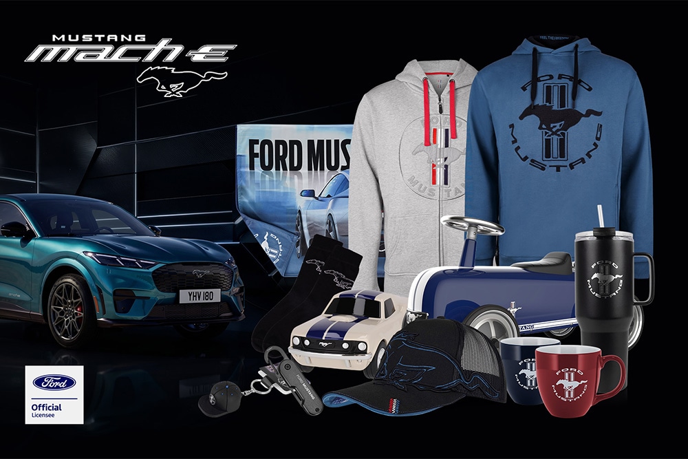 Colección de productos de Ford en la que aparecen diversos vehículos de la marca como fondo, con paraguas, tazas y prendas de ropa con el logotipo de Ford.