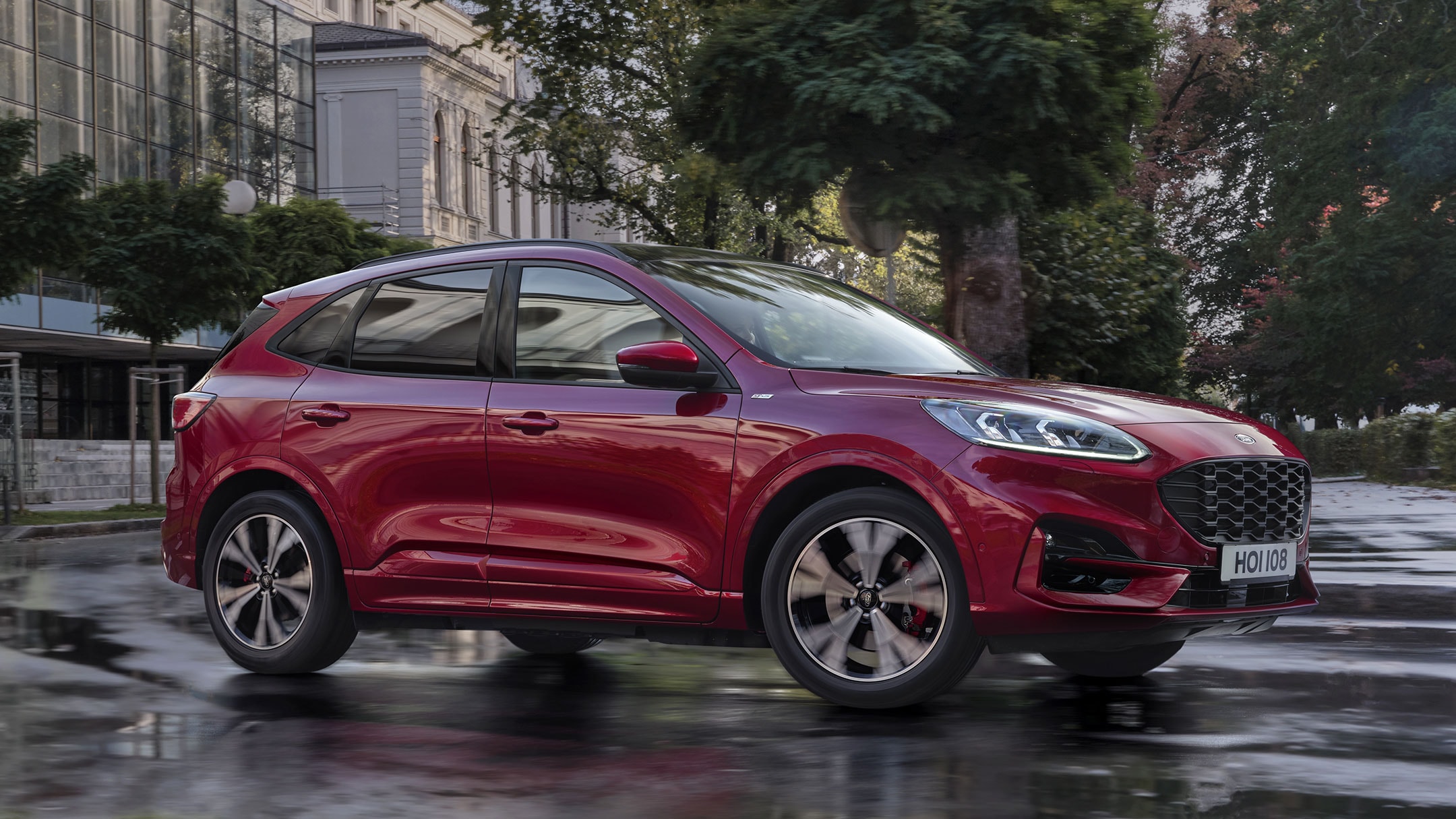 Red Ford Kuga parked in front of buildings and trees