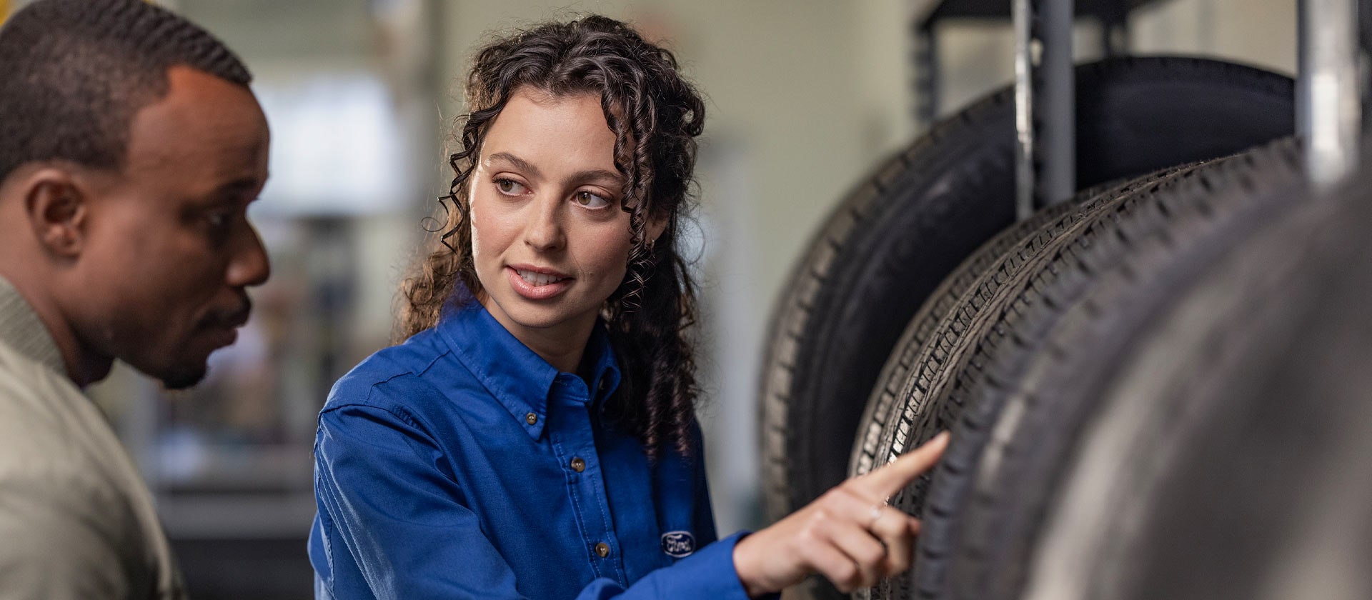 Un especialista en reparaciones de Ford ayuda a un cliente con neumáticos nuevos para coches Fiesta