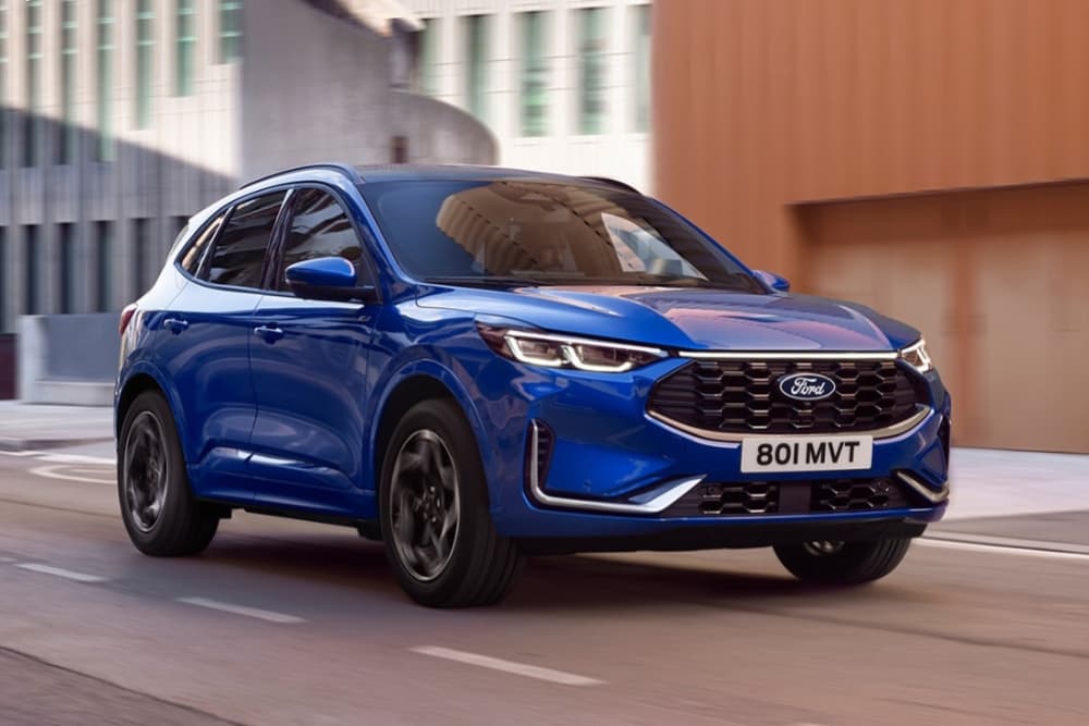 Un SUV híbrido enchufable Ford Kuga azul aparcado en una pintoresca carretera de montaña.
