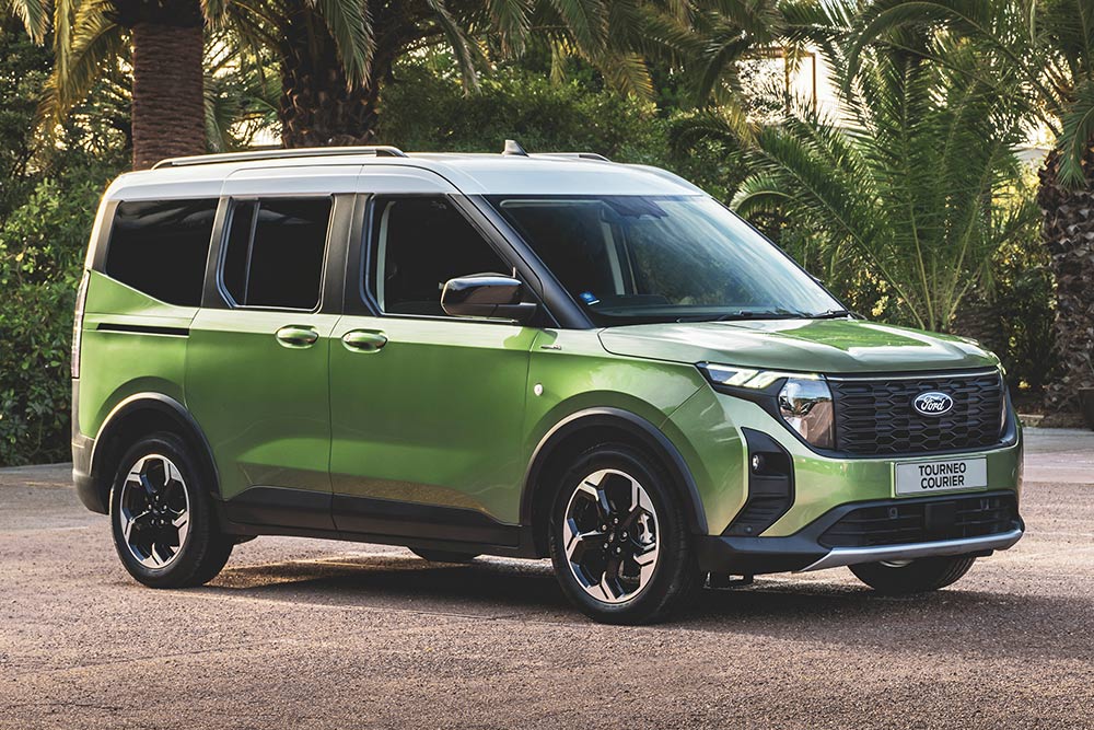 Una camioneta Ford Tourneo Courier verde estacionada afuera de un edificio de oficinas.