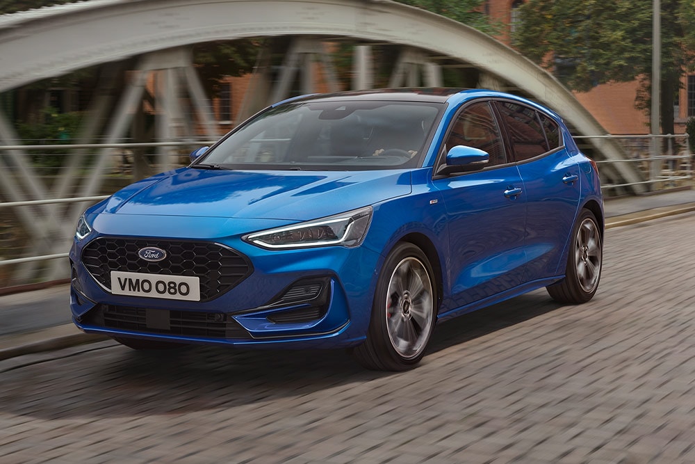 Un Ford Focus hatchback azul conduciendo sobre un puente.