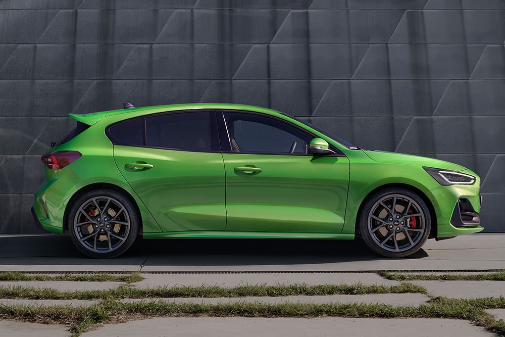 El costado de un Ford Focus ST hatchback verde estacionado fuera de la carretera.