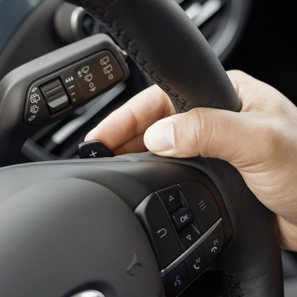 Un primer plano de una mano operando las levas de cambio del Ford Focus detrás del volante.