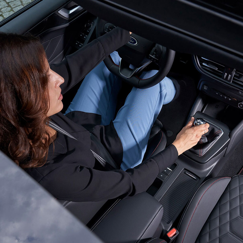 Una vista aérea del conductor sentado en el Ford Focus, tomada a través del techo panorámico de vidrio.