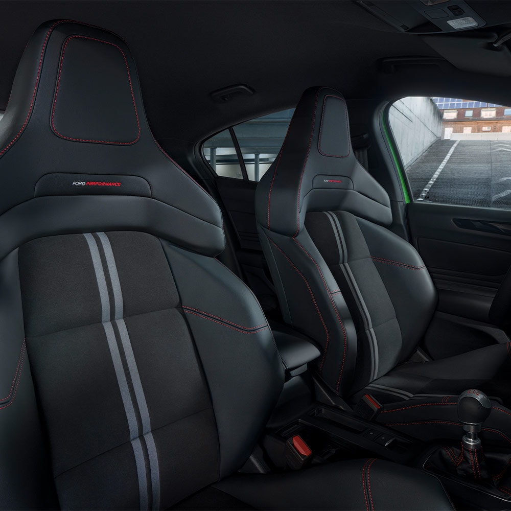 Un primer plano de los asientos deportivos del Ford Focus ST, con tapicería oscura con costuras rojas en contraste.