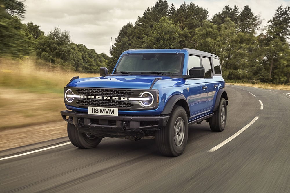 Vista delantera del nuevo Ford Bronco azul que recorre un camino rural.