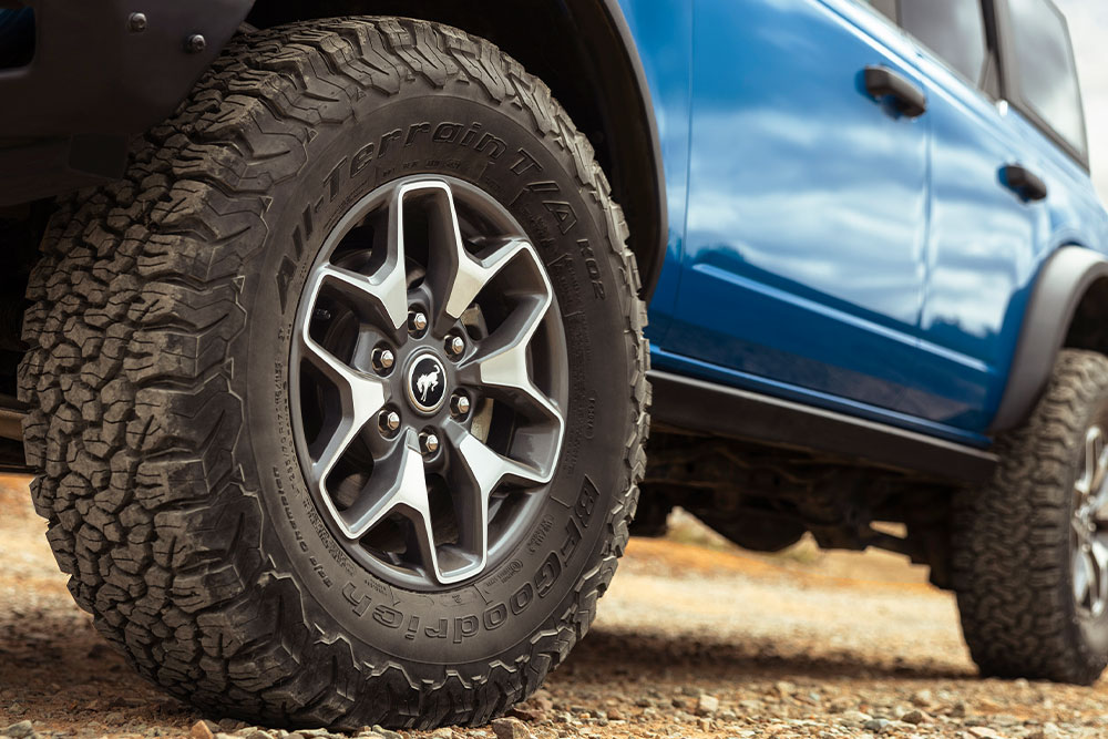 Primer plano de los neumáticos todoterreno de un Ford Bronco azul.
