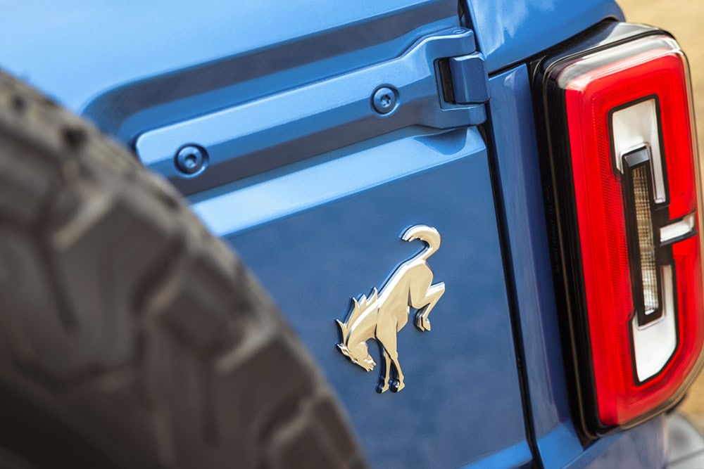 Un primer plano de los logotipos de la marca en la parte trasera de un Ford Bronco azul.