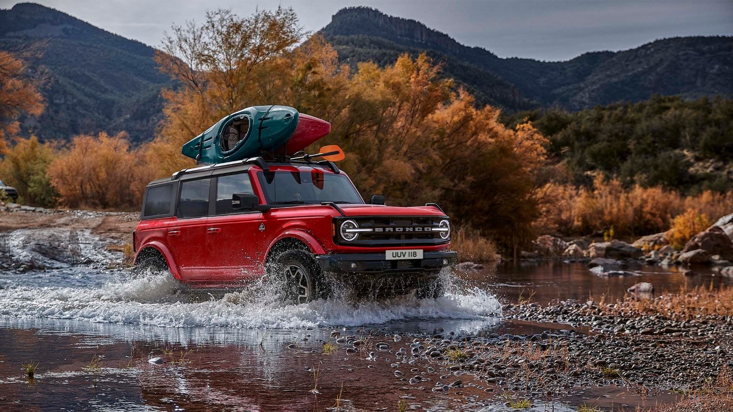 Ford Bronco atravesando un río entre montañas