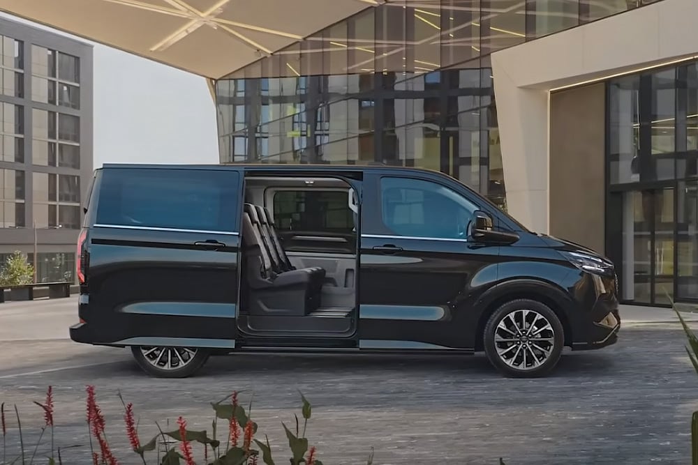 Un Ford E-Tourneo Custom negro aparcado con la puerta lateral abierta, dejando ver los asientos interiores.