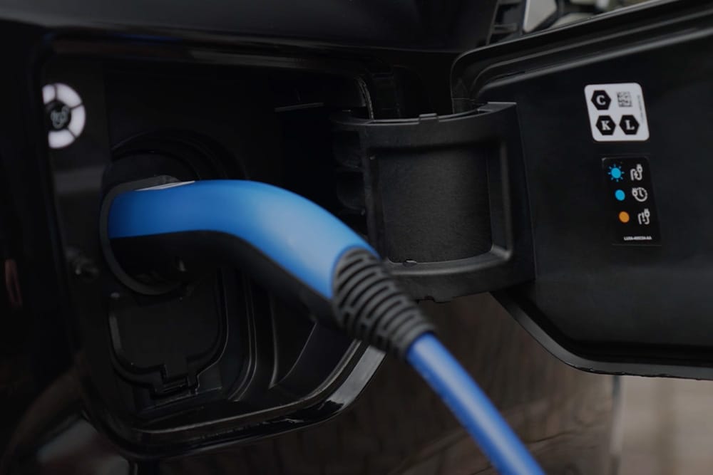 Primer plano de un cable de carga azul conectado a un puerto de carga de un vehículo eléctrico.
