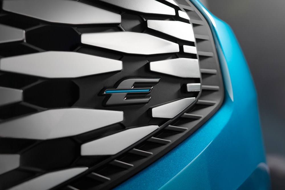 Primer plano de la rejilla del Ford E-Tourneo Custom, con el logotipo azul «E» exclusivo de los vehículos eléctricos Ford.