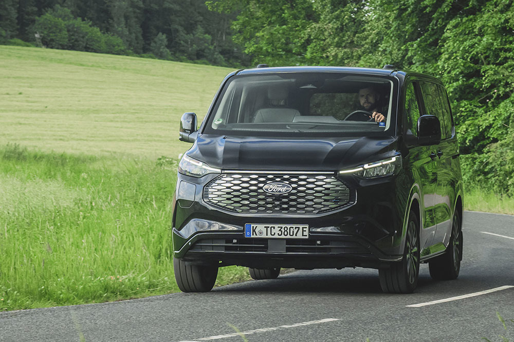 Un Ford E-Tourneo Custom negro circulando por una carretera rural.