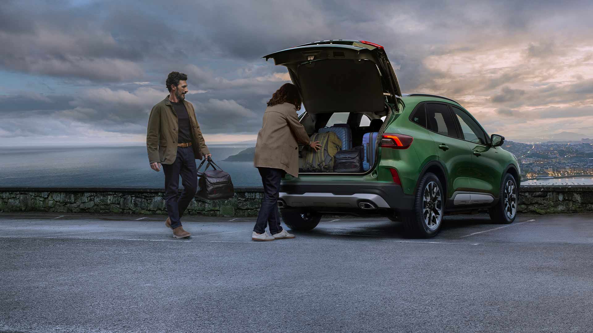 Imagen de dos personas que cargan varias maletas en el espacioso maletero del Ford Kuga. 