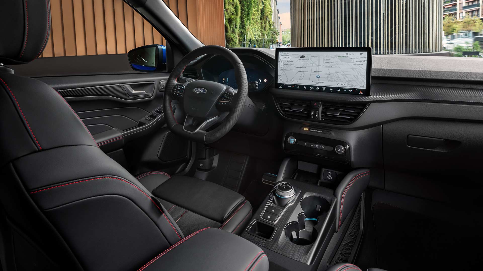 Interior del Ford Kuga con el volante con el logo Ford, la pantalla táctil SYNC® 4 y los asientos negros con pespuntes rojos.