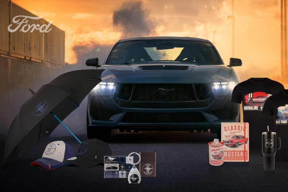 Colección de productos Ford con varios vehículos Ford como telón de fondo, incluyendo paraguas, tazas y prendas de vestir con la marca Ford.