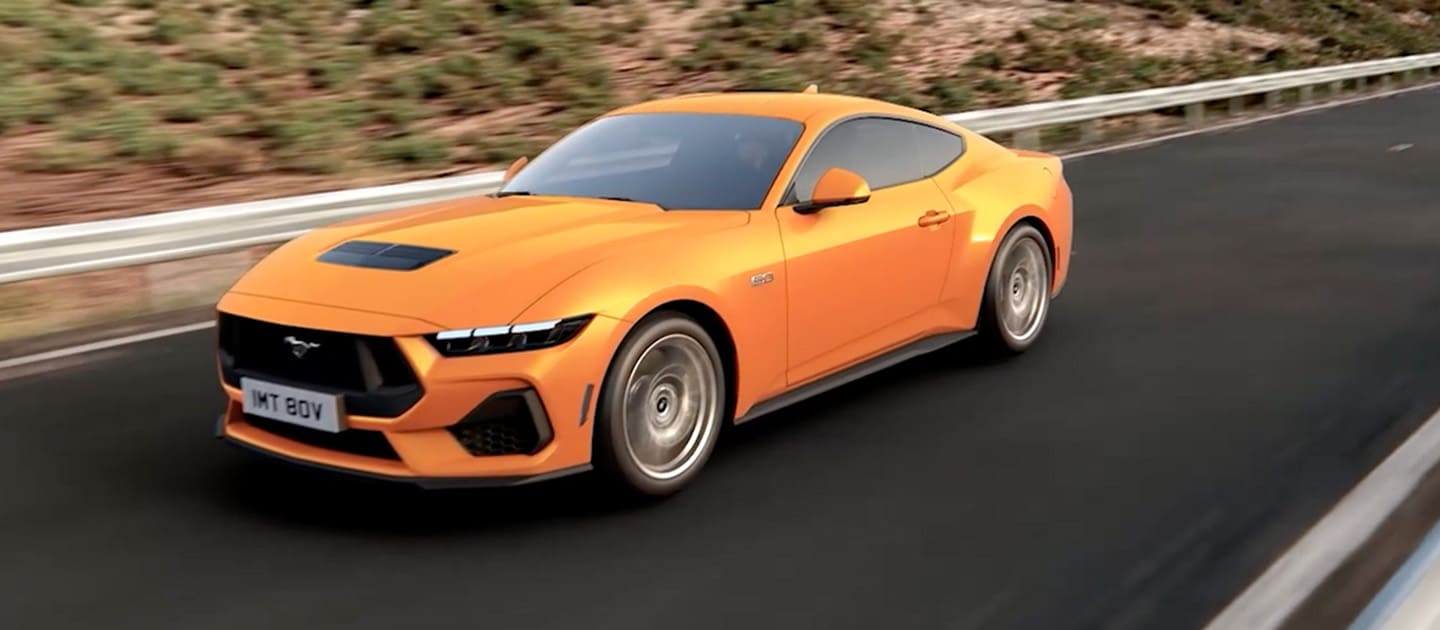 Ford Mustang GT Fastback en color Orange Fury circulando por una carretera de montaña