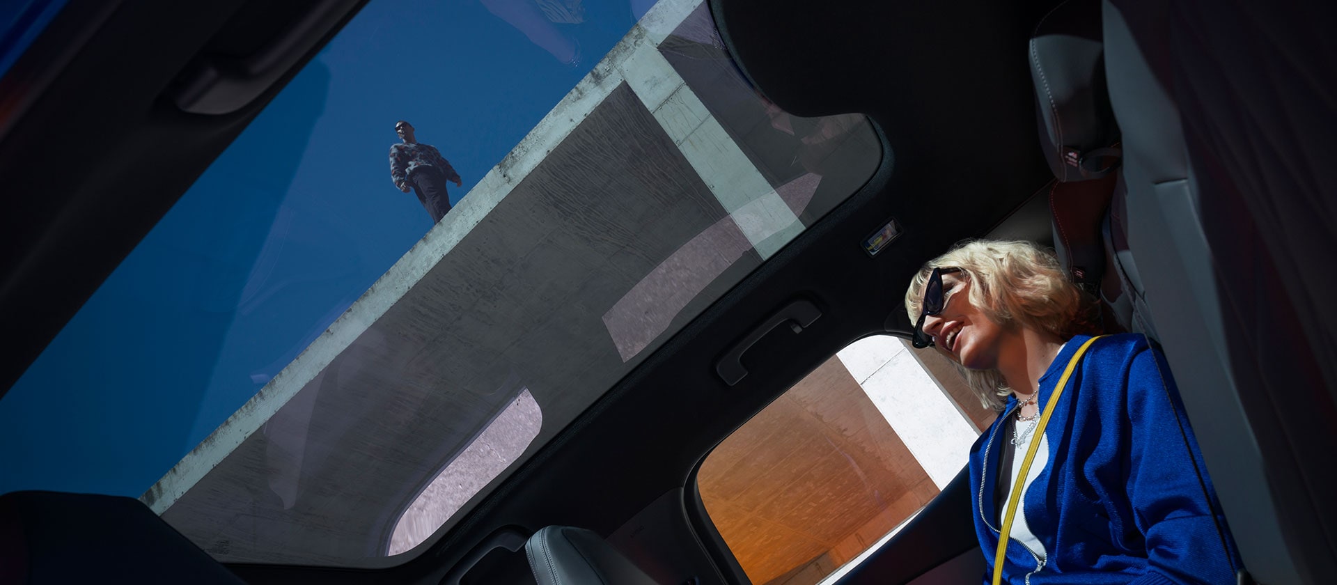 Persona sentada en el interior del nuevo Ford Capri® disfrutando del techo panorámico de cristal.