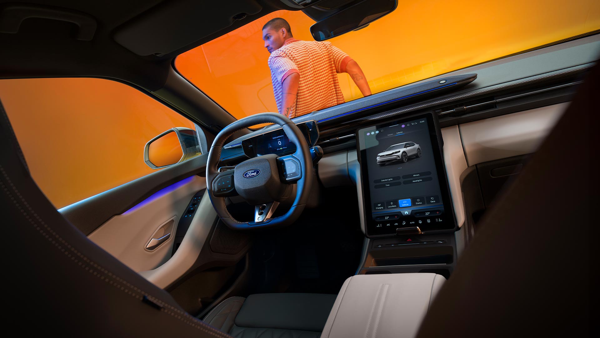 Interior de un Ford Capri aparcado en un estudio de fotografía con fondo de color amarillo. En la imagen puede verse asimismo a un hombre apoyado sobre el capó del vehículo.