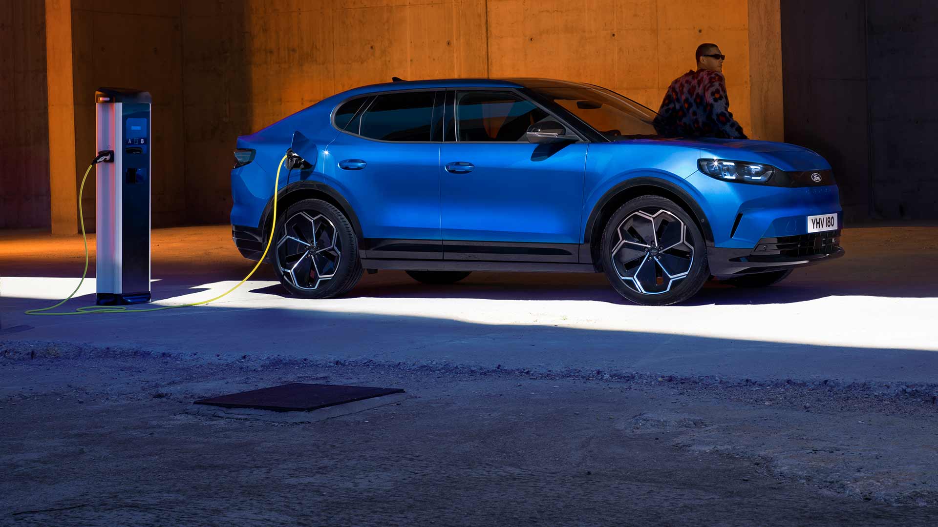 Ford Capri® eléctrico azul conectado a un punto de carga público para vehículos eléctricos.