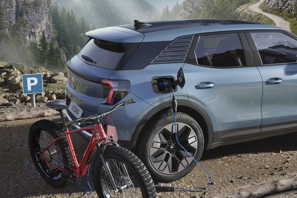 Una bicicleta eléctrica cargando desde una Ford Explorer®, con un paisaje montañoso de fondo.