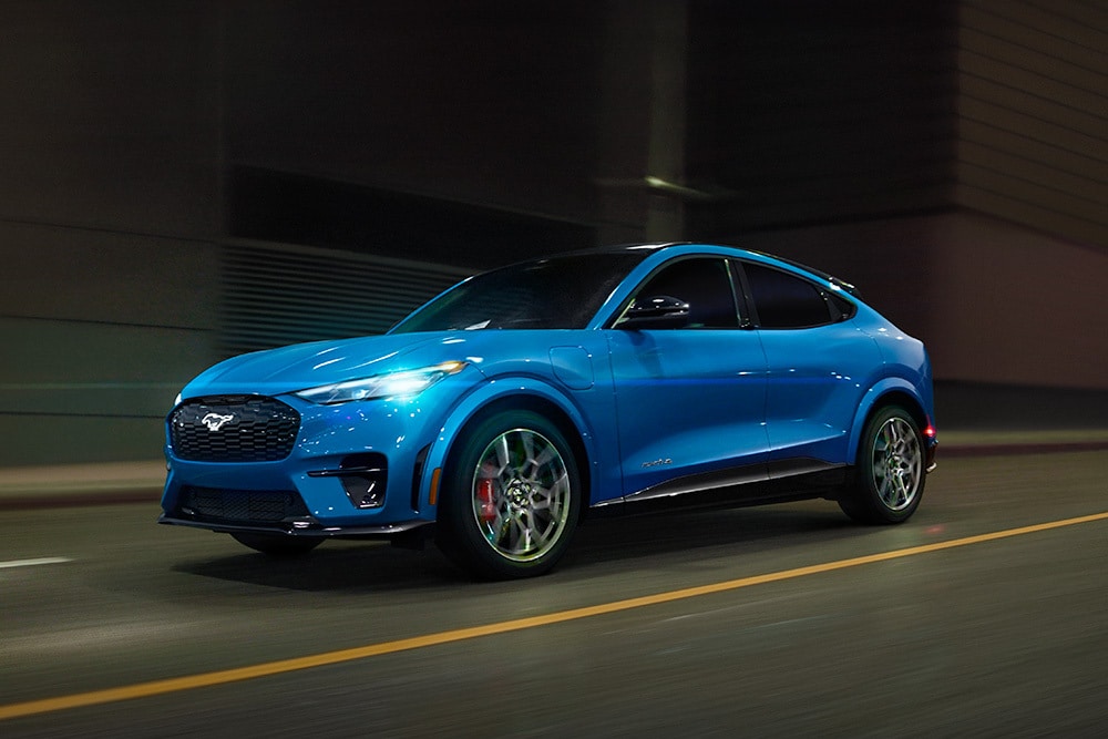Un deportivo eléctrico Ford Mustang Mach-E GT azul circulando por una carretera.